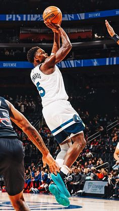 a basketball player jumping up to dunk the ball in front of two other players