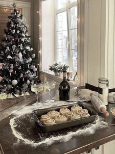 a christmas tree in the corner of a kitchen next to a cookie sheet with frosting on it