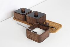 two salt and pepper shakers sitting on top of a wooden tray next to a cork coaster