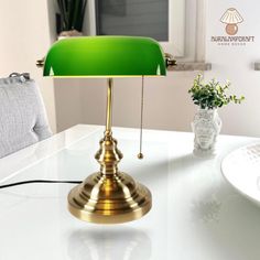 a green lamp sitting on top of a white table next to a potted plant