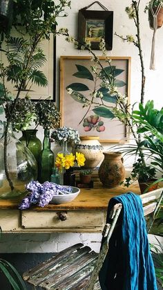 a table topped with lots of potted plants and vases next to each other