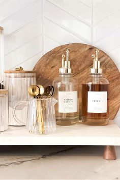 bottles and containers sit on a shelf in front of a white tiled wall with gold accents