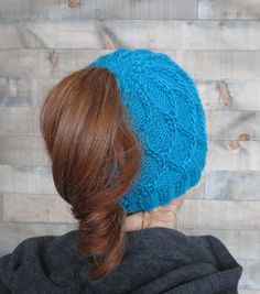 a woman with red hair wearing a blue knitted hat on top of her head