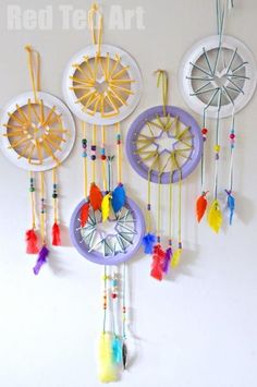 a group of colorful dream catchers hanging on a wall next to a white wall