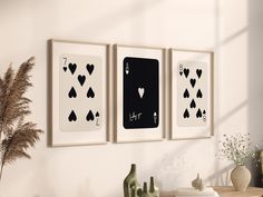 three black and white playing cards hanging on the wall next to a vase with flowers