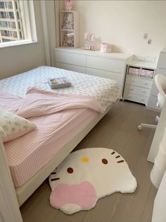 a bedroom with a hello kitty rug on the floor next to a bed and dresser