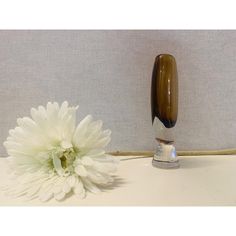 a white flower sitting on top of a table next to a vase with a brown handle