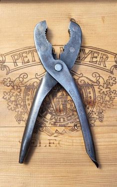 a pair of pliers sitting on top of a wooden table next to a bottle opener