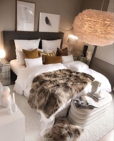 a bedroom with white bedding and fur rugs on the floor in front of it