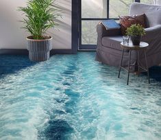 a living room with blue water flooring and a couch in the corner next to a potted plant