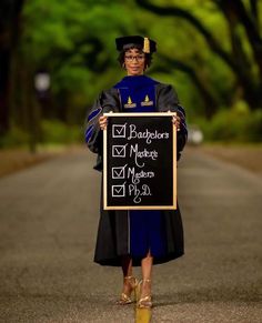 a woman in graduation gown holding a sign