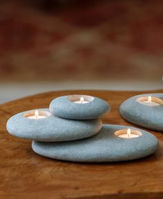 three lit candles are placed on top of some rocks and one is in the shape of a heart