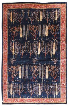 an antique rug with trees and leaves on it, in blue tones that are hand - knotted