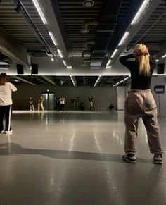 two people standing in an empty room with their hands on their head and arms behind them