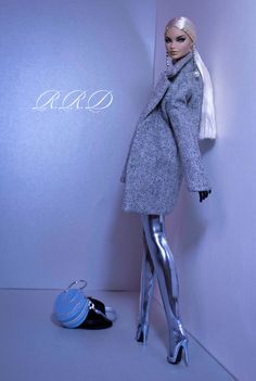 a mannequin dressed in shiny silver clothing next to a wall with the word aco written on it