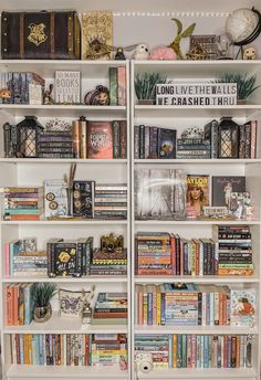 a book shelf filled with lots of books on top of white shelves in a room