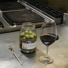 a glass of wine and some olives on a counter