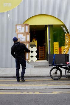 a man pushing a cart with boxes on it down the street in front of a store