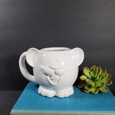 a white mug sitting on top of a book next to a succulent plant