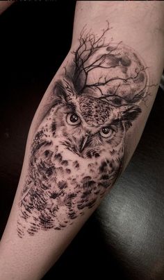 an owl tattoo on the arm with trees and branches around it's eyes,