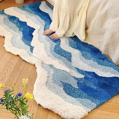 a woman sitting on the floor in front of a blue and white rug with waves