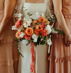 the bridesmaids are holding their bouquets with orange and white flowers on them