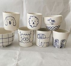 nine ceramic bowls with designs on them are lined up against a white background, one has a dog and the other has a bird