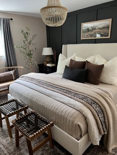 a bedroom with a bed, two chairs and a chandelier hanging from the ceiling