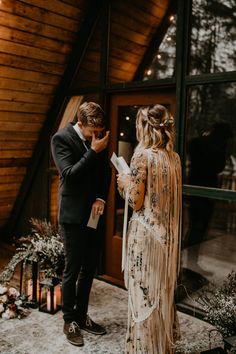 a couple getting married in front of a wooden building with lights on the roof and decorations around them