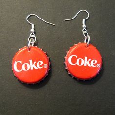 coca cola bottle cap earrings with the word coke in white letters on red and black background