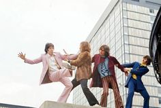 an image of the beatles dancing in front of a building with skyscrapers behind them