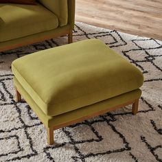 a green chair and footstool sitting on top of a rug