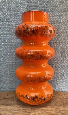 an orange vase sitting on top of a wooden table