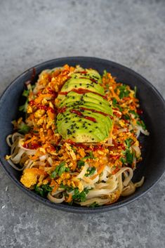 a bowl filled with noodles, avocado and other toppings on top of it