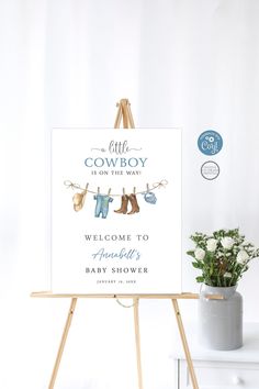 a welcome sign for a baby shower with clothes hanging on a line and flowers in a pot