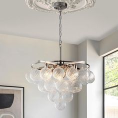 a chandelier hanging from the ceiling in a room with white walls and windows