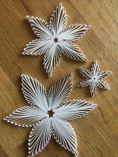 three white paper flowers sitting on top of a wooden table