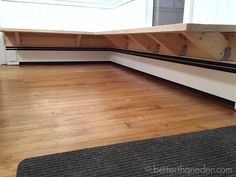 an empty room with wooden flooring and benches on the bottom half of the wall