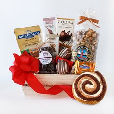 a basket filled with lots of different types of food and snacks next to a red ribbon