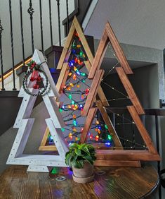 three wooden christmas trees sitting on top of a table next to a bannister