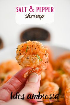 a hand holding up a piece of food with shrimp on it and the caption reads salt & pepper shrimp life's ambrosia