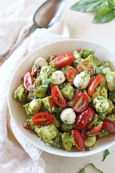 a white bowl filled with vegetables on top of a table next to a spoon and napkin