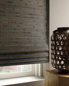 a bamboo blind in front of a window with the blinds pulled back to reveal an intricate design