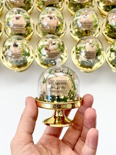 a hand is holding a bell in front of many christmas ornaments