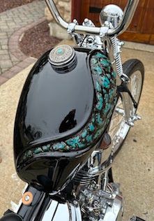 a black motorcycle parked on top of a sidewalk next to a wooden door and brick walkway