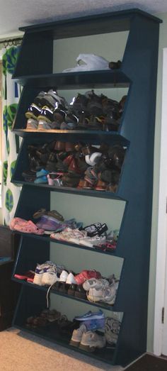 there is a shelf with shoes on it in the living room, next to a window