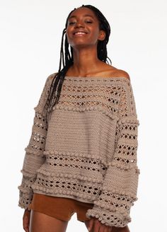 a woman with dreadlocks is smiling and wearing an off the shoulder sweater that has crochet on it