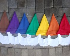 a row of colorful hats sitting on the side of a brick wall