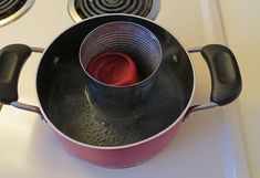 a pot with a red candle inside on the stove top next to two burners