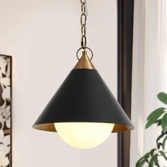 a black and gold pendant light hanging from a metal chain in a living room area